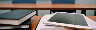 Stack of books and a tablet on a classroom table